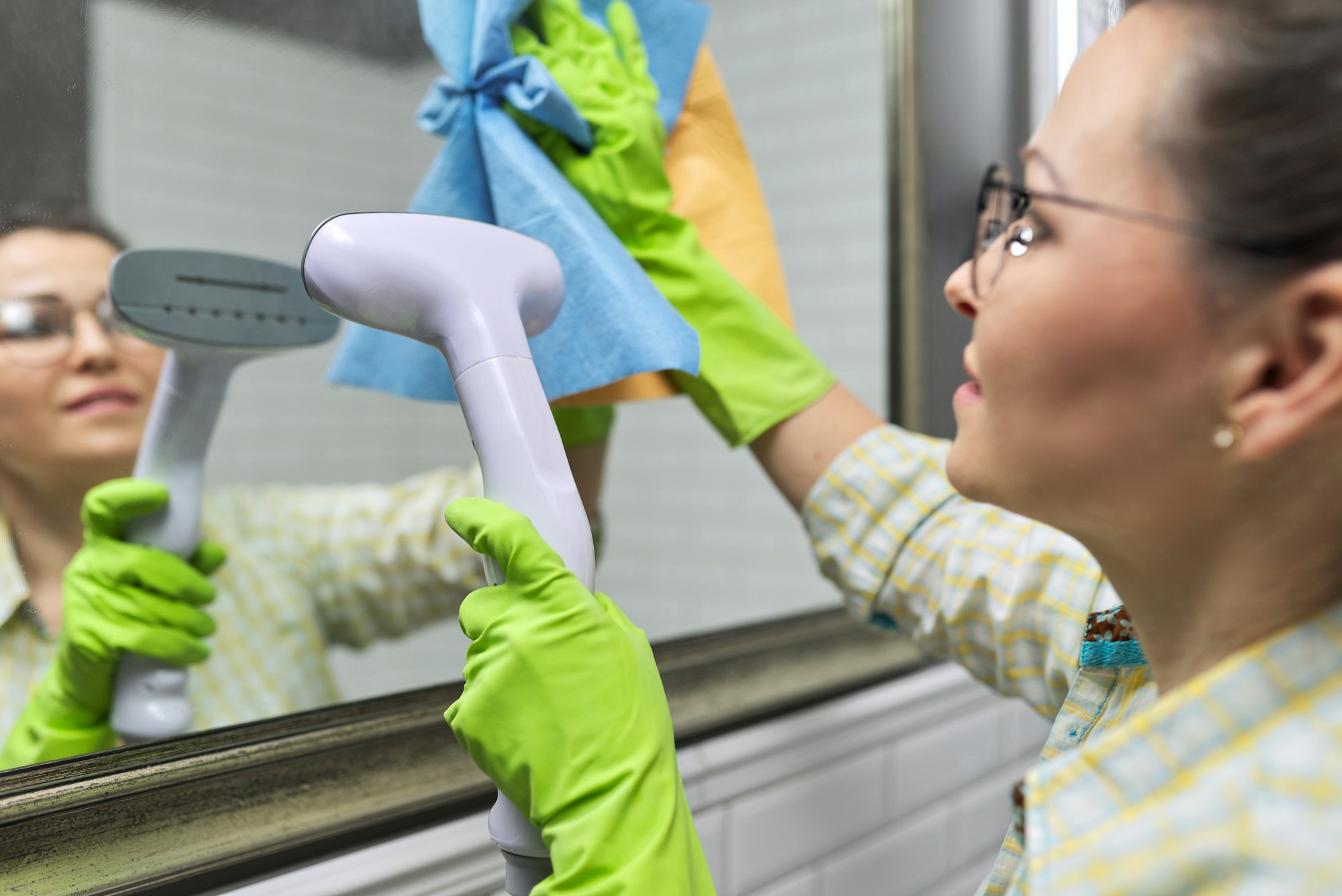 Close-up of gloved hands with steam in mirror, eco-friendly cleaning